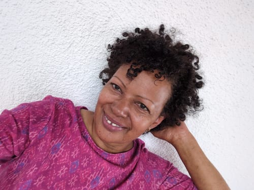 Customer with defined natural curls leaning against a white wall